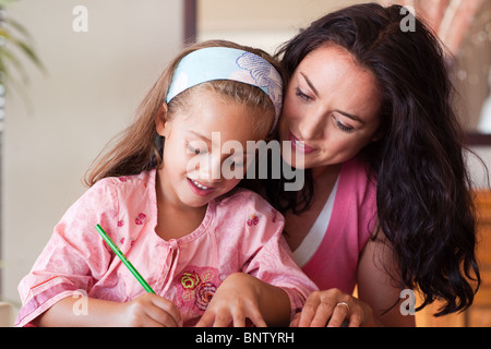 Madre concentrata di aiutare la propria figlia per i compiti a casa Foto Stock