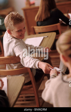 Gli studenti passando una nota in aula Foto Stock