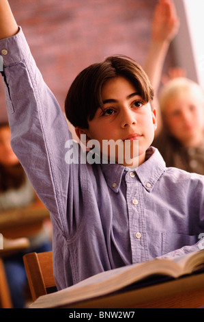 Scuola elementare studente alzando la mano in aula Foto Stock