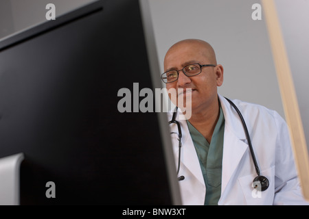 Medico guardando il monitor di un computer Foto Stock