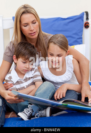 Madre la lettura di un libro con i suoi bambini Foto Stock