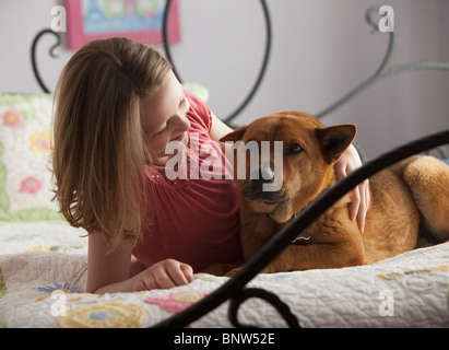 Ragazza giovane sdraiato sul letto con il cane Foto Stock