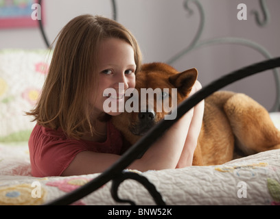 Ragazza giovane costeggiata cane sul letto Foto Stock