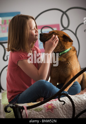 Giovane ragazza che gioca con il cane sul letto Foto Stock