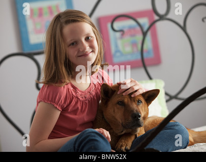 Giovane ragazza rilassante con il cane sul letto Foto Stock