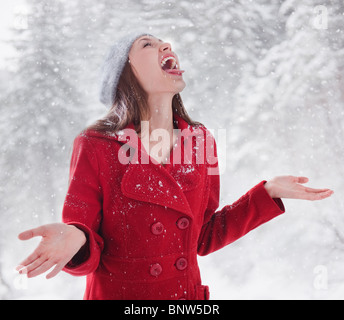 Donna che cerca di catturare la neve sulla sua lingua Foto Stock