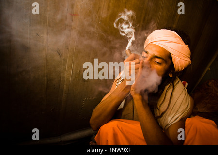 Un sadhu fuma un chillum (marijuana) durante il festival indù del Kumbh Mela, Haridwar, India. Foto Stock