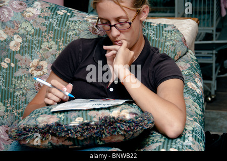 Un adolescente ragazza caucasica si concentra come lavora un puzzle Suduko. Foto Stock