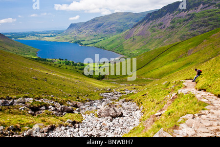 Uno sfinito walker si appoggia per ammirare la vista su Wast Water dalla testa Wasdale rotta verso Scafell Pike, Lake District, Cumbria, Regno Unito Foto Stock