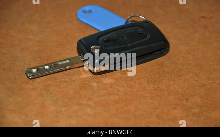 Le chiavi dell'auto, auto chiave (Peugeot) senza logo - con portachiavi - sfondo marrone Foto Stock