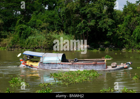 Caricato pesantemente barca fluviale sul fiume Chao Praya River a Ayuttaya in Thailandia. Cluster di giacinto di acqua floating lungo. Foto Stock