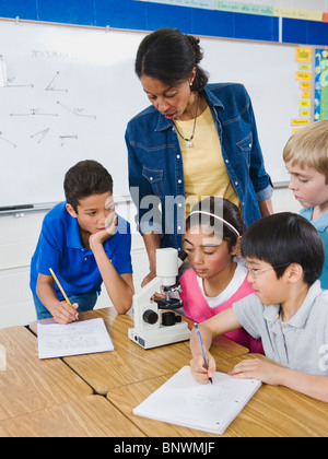 Insegnanti e studenti elementari guardando al microscopio Foto Stock