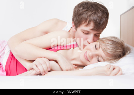 Uomo di baciare la donna a letto Foto Stock