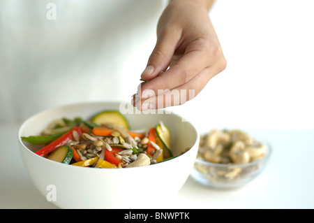 Mano spargendo i semi di girasole su di verdure Foto Stock