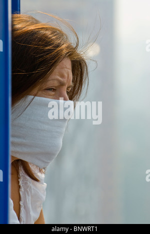 Muscovite donna in maschera protettiva guardando da una finestra Foto Stock