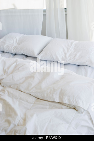 Letto con lenzuola bianche Foto Stock