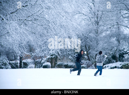 Una giovane coppia gioca nella neve fresca, lanciando palle di neve in un paesaggio innevato in Byron Park, Harrow, un quartiere di Londra. Foto Stock