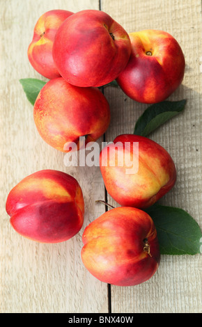 Mature le pesche noci su una tavola di legno Foto Stock