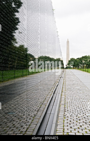 Vietnam Veterans Memorial Washington DC // WASHINGTON DC - i visitatori osservano il Vietnam Veterans Memorial sul National Mall di Washington DC. Progettato da Maya Lin e dedicato nel 1982, il monumento è costituito da due pareti di granito nero che mostrano i nomi di più di 58.000 americani morti o dispersi durante la guerra del Vietnam. La superficie lucida crea riflessi dei visitatori, mentre vedono i nomi disposti cronologicamente sul monumento commemorativo a forma di V. Foto Stock