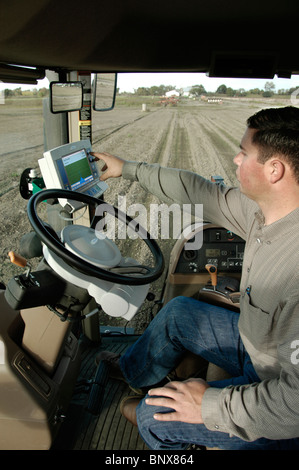 Un conducente del trattore con la navigazione GPS per campo accurata cernita. Foto Stock