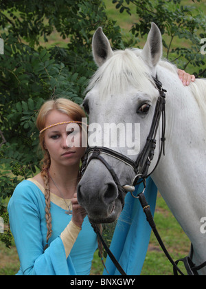 Ragazza slava in russo vestito con il suo cavallo bianco Foto Stock