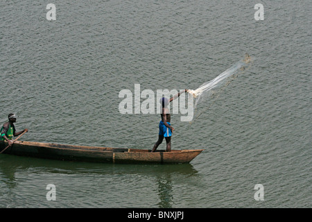 Un pescatore di fusione il suo net dal suo canoa sul lago Victoria, Uganda Foto Stock