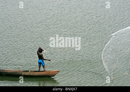 Un pescatore di fusione il suo net dal suo canoa sul lago Victoria, Uganda Foto Stock