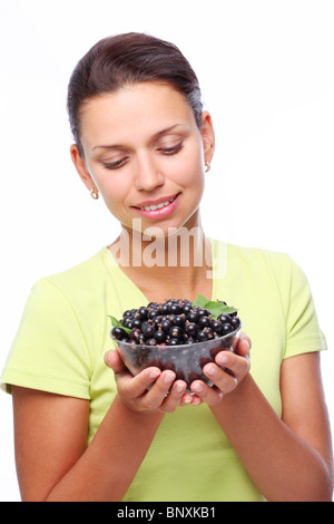 Sorridente giovane donna con ciotola piena di ribes nero nelle sue mani. Foto Stock