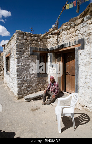 Un uomo di posti a sedere di fronte alla sua casa in un piccolo villaggio lungo la strada tra Leh e Tsomoriri in Ladakh, India. Foto Stock