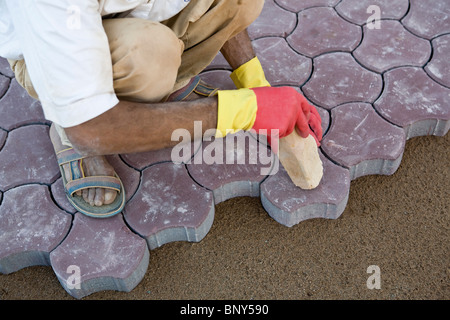 L'uomo installazione ad incastro di pietre per pavimentazione sul terreno in modo da creare il marciapiede, Ouled Berhil, Marocco Foto Stock