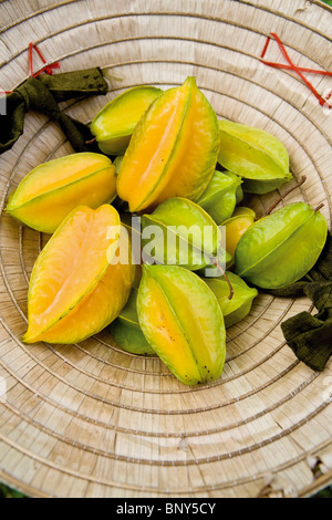 Appena raccolto starfruit in un tradizionale vietnamita hat Foto Stock