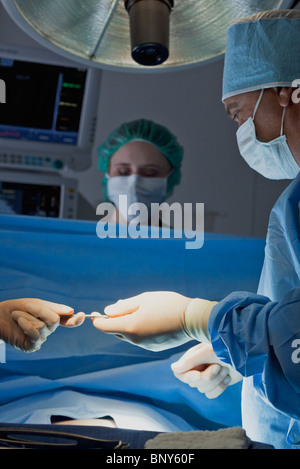 Consegna dello strumento chirurgico al chirurgo durante il funzionamento Foto Stock