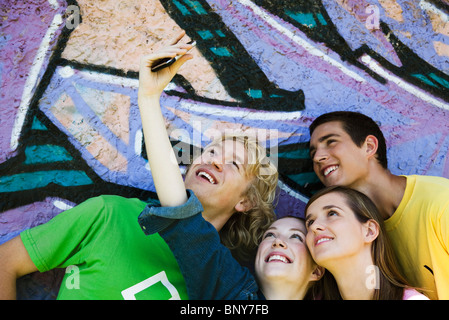 Teen ragazza utilizzando il telefono cellulare per fotografare se stessa con gli amici Foto Stock