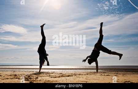 Due persone cartwheeling sulla spiaggia Foto Stock