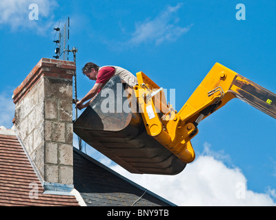 Antenna televisione essendo dotato di camino dall uomo in piedi (nessuna attrezzatura di sicurezza) in JCB movimentatore telescopico benna - Francia. Foto Stock