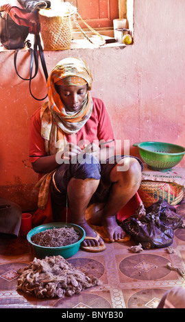 Donna malgascia rendendo filo di seta strofinandola sulla sua coscia, Antemoro fabbrica di seta, nel sud-est del Madagascar Foto Stock