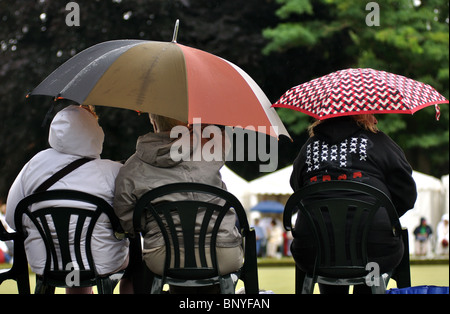 Persone con ombrelloni signore guardare partite di bocce Foto Stock