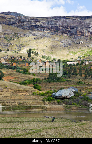 Uno scenario tipico negli altopiani centrali del Madagascar, che un borgo collinare con terrazze che conducono in basso verso una paddyfield Foto Stock