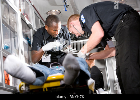 I paramedici la cura per il paziente sulla barella in ambulanza Foto Stock