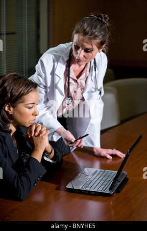 Medici di sesso femminile esaminando e discutendo di laptop Foto Stock