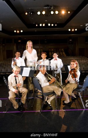 Giovani studenti suonare strumenti musicali in auditorium scuola con l'insegnante Foto Stock