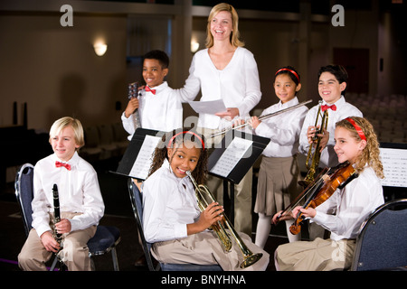 La scuola dei bambini suonare strumenti musicali in band con insegnante Foto Stock