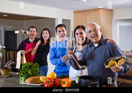 Tre generazioni della famiglia ispanica cucinare insieme nella cucina di casa Foto Stock