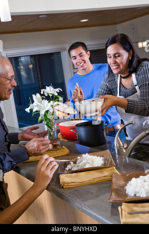 Madre ispanica che serve cena di famiglia in cucina Foto Stock