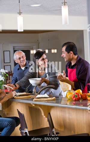 Madre ispanica che serve cena di famiglia in cucina Foto Stock