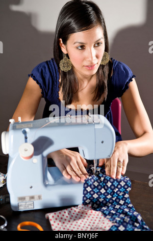 Giovane donna tessuto cucitura con la macchina da cucire Foto Stock