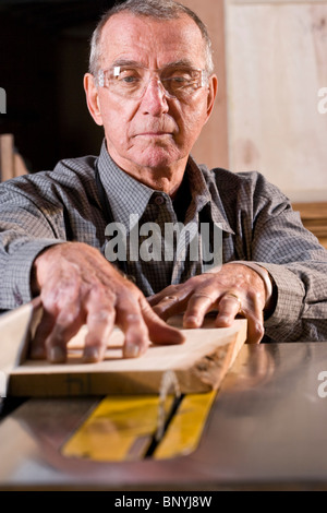 Senior uomo in macchine per la lavorazione del legno negozio utilizzando sega da tavolo Foto Stock