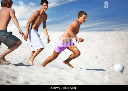 Giovani uomini che giocano a calcio sulla spiaggia. Foto Stock