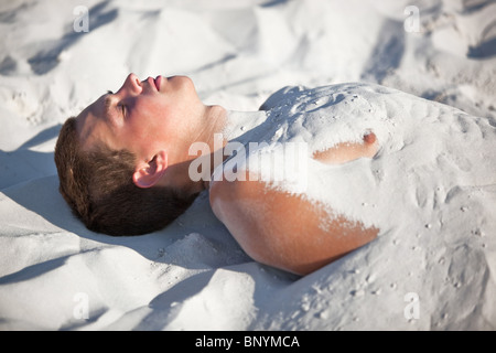 Giovane uomo sepolto nella sabbia. Foto Stock