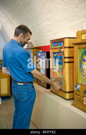 L'uomo gioca un penny slot machine nelle memorie meccanica Museo di divertimenti, Kings Road archi, Brighton Foto Stock